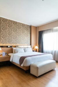 A neatly organized hotel room with an open suitcase, personal pillow, and a pair of slippers by the bed.